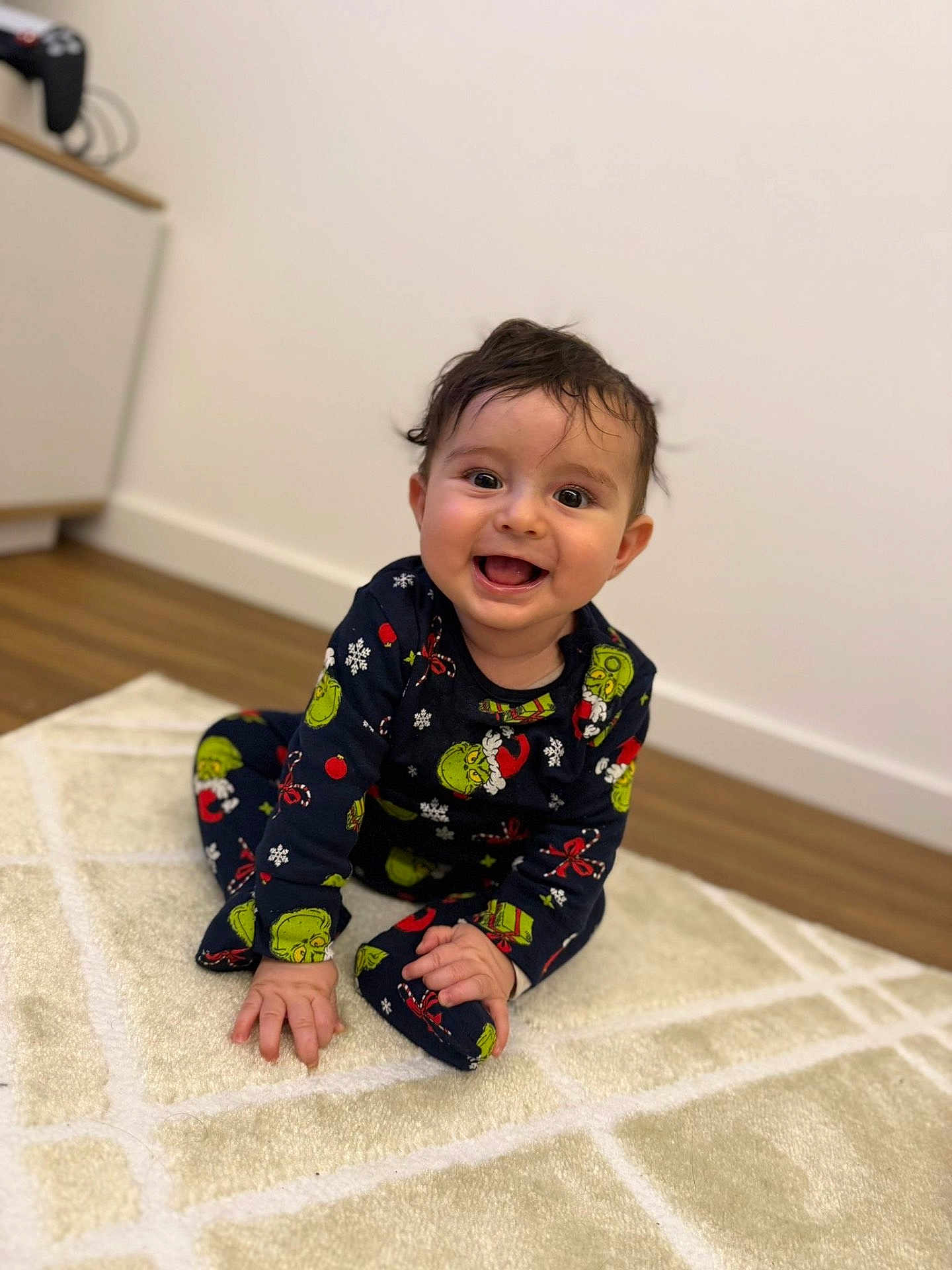 Noah participe au concours pour gagner de l'argent avec cette photo : baby, child, smiling, pajamas, grinch, indoor, carpet, rug, floor, wooden_floor, happy, cute, toddler, clothing, person, portrait, sitting, face, hair, home