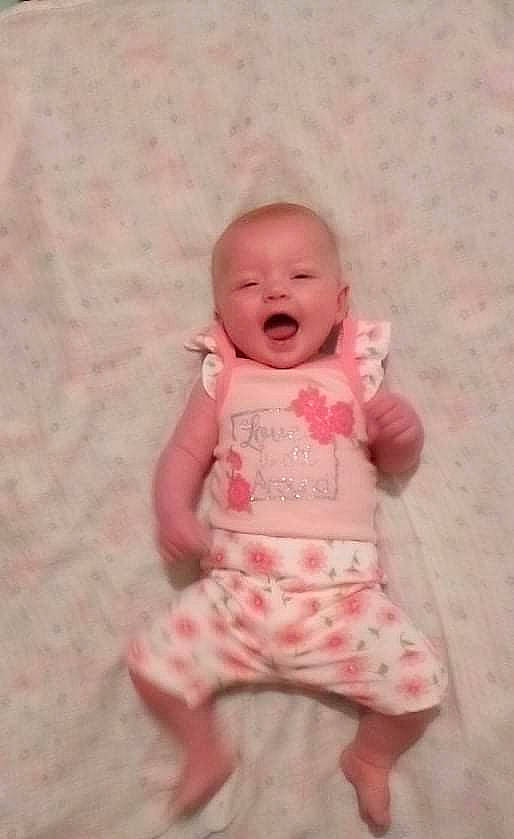 Izzy is registered to the contest to win money with this photo: arm, baby, baby_toddler_clothing, cheek, child, eye, foot, happy, human_body, human_leg, iris, lip, peach, person, pink, skin, sleeve, smile, thumb, toddler