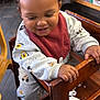 toddler, child, high_chair, smiling, happy, mickey_mouse, bib, curly_hair, sneakers, wooden_furniture, restaurant, indoor, cute, playful, clothing, person, seat, joyful, baby, casual