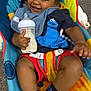 baby, smiling, bottle, milk, baby_chair, fisher_price, clothing, socks, happy, child, indoor, colorful, bib, toddler, person, seatbelt, toy, furniture, face, cute