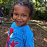 child, toddler, smiling, happy, outdoor, playground, portrait, spiderman, superhero, blue_shirt, curly_hair, dark_skin, close_up, standing, trees, nature, bokeh, background_child, play_area, daylight