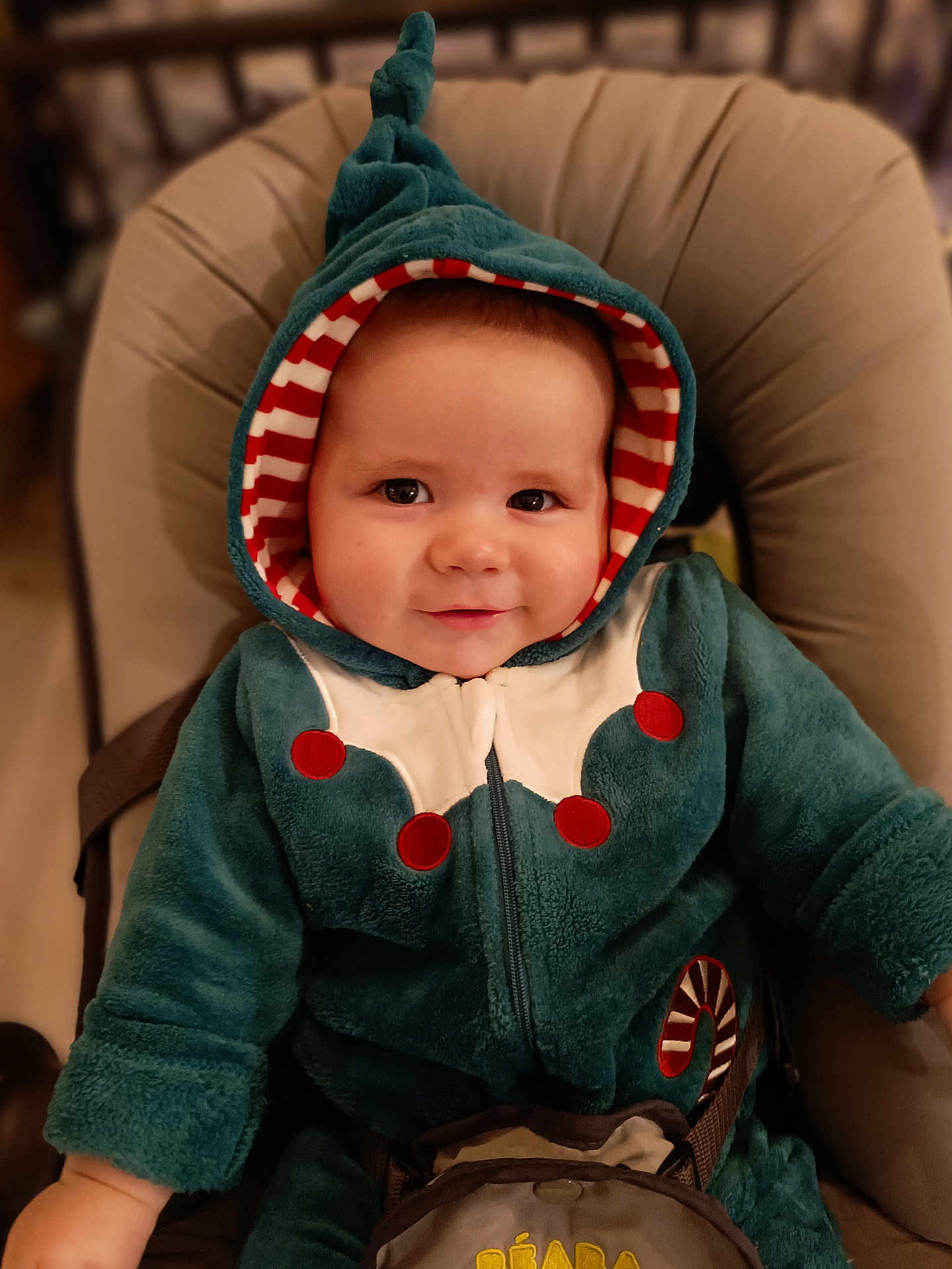 Ezra participe au concours pour gagner de l'argent avec cette photo : baby, child, smiling, hood, jacket, cozy, seated, infant, face, cute, red, white, teal, striped, candy_cane, clothing, indoor, portrait, young, person