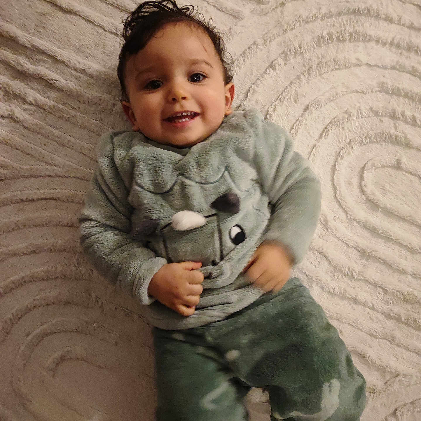 Amir participe au concours pour gagner de l'argent avec cette photo : baby, barefoot, carpet, child, cozy, cute, fun, green_clothing, happy, indoor, laying, pants, person, playful, portrait, smile, sweater, texture, toddler, young_child