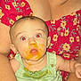 Winona is registered to the contest to win money with this photo: baby, food, messy, red_eye, adult, floral_dress, holding, surprised, face, clothing, hand, skin, expression, infant, feeding, green_shirt, person, portrait, indoor, closeup
