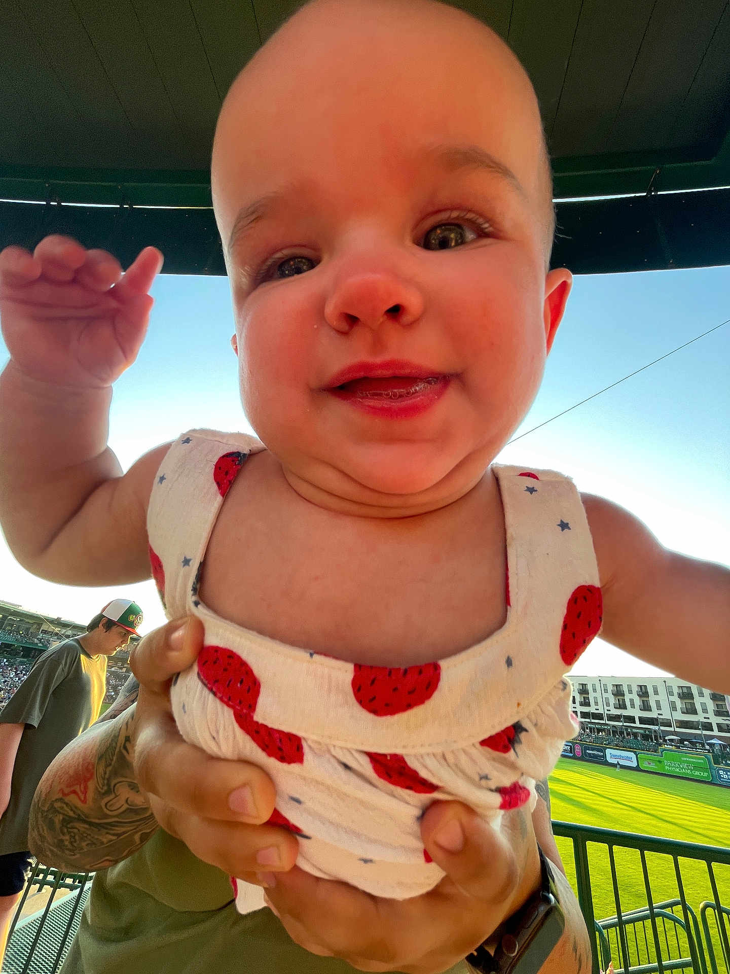 Winona joined the competition — help win amazing prizes! baby, child, person, outdoor, stadium, field, grass, hand, tattoo, dress, pattern, happy, smile, face, people, spectator, sunlight, daytime, hat, fence