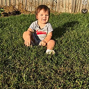 James is registered to the contest to win money with this photo: baby, casual_clothing, child, cute, daylight, grass, greenery, happy, nature, outdoor, person, playing, portrait, shirt, sitting, smiling, summer, sunlight, toddler, young_child