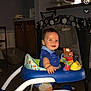 baby, blue_shirt, cabinet, child, floor, footwear, furniture, happy, home, indoor, living_room, person, playtime, shorts, smiling, standing, toddler, toy, walker, wooden_floor