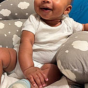 Jamari is registered to the contest to win money with this photo: baby, blanket, child, cloud_pattern, comfort, cushion, cute, expression, footwear, hand, happy, indoor, infant, onesie, person, portrait, seated, skin, smile, sock