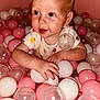 Lillyann is registered to the contest to win money with this photo: baby, child, ball_pit, pink_balls, white_balls, translucent_balls, playing, cute, onesie, fruit_pattern, happy, smiling, indoor, person, infant, hands, face, head, skin, closeup