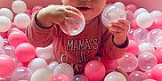 Lillyann joined the competition — help win amazing prizes! baby, child, ball_pit, pink_balls, white_balls, transparent_balls, indoor, play, cute, smiling, happy, long_sleeve_shirt, person, face, hand, closeup, infant, toddler, toy, playtime