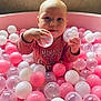baby, child, ball_pit, pink_balls, white_balls, transparent_balls, indoor, play, cute, smiling, happy, long_sleeve_shirt, person, face, hand, closeup, infant, toddler, toy, playtime