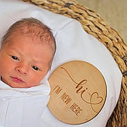 David joined the competition — help win amazing prizes! newborn, baby, infant, blanket, blue_ribbon, basket, woven_basket, wooden_plaque, text, face, head, eyes, skin, swaddled, white_blanket, portrait, indoors, cute, announcement, calm