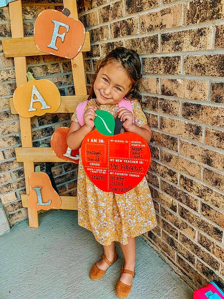 Madison joined the competition — help win amazing prizes! baby_toddler_clothing, brick, child, dress, eye, flooring, fun, happy, joy, leisure, logo, orange, pattern, peach, person, play, room, sandal, sitting, smile