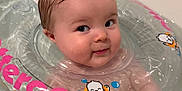Stevie joined the competition — help win amazing prizes! baby, bathtub, water, inflatable_ring, wet_hair, smile, face, child, cute, floating, bath_time, plastic, transparent, cartoon, toy, playful, skin, hand, pink_text, orange_text