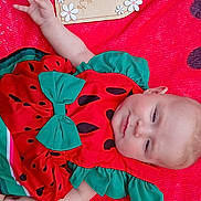 Lainey joined the competition — help win amazing prizes! baby, infant, watermelon_outfit, red_blanket, decorative_sign, flowers, milestone, cute, lying_down, smiling, child, portrait, celebration, hand_up, clothing, baby_girl, face, skin, happy, resting