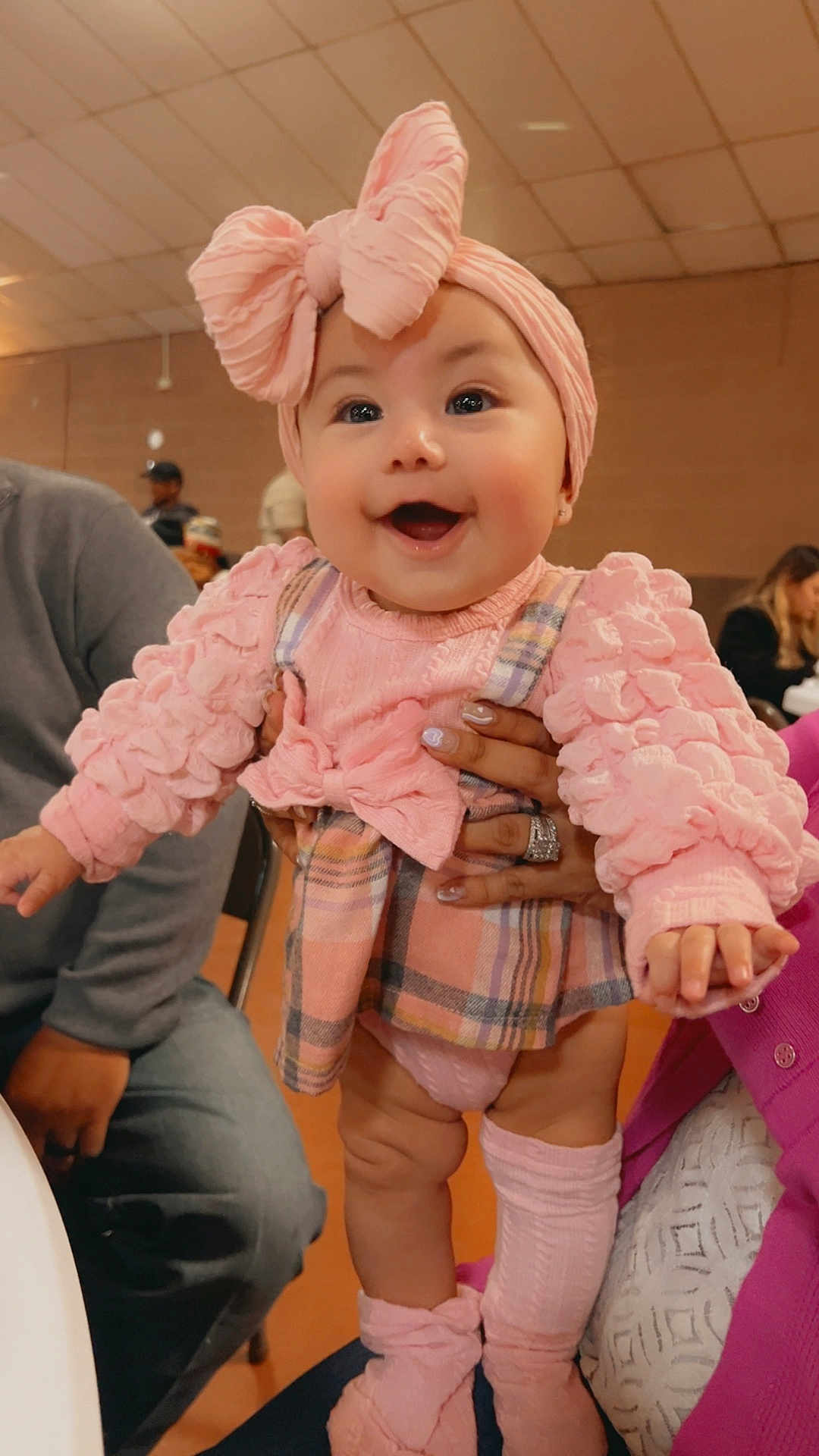 Stormi joined the competition — help win amazing prizes! baby, child, pink_clothing, headband, smiling, indoor, person, hands, adult, plaid_skirt, socks, cute, happy, infant, fashion, portrait, family, celebration, people, seated