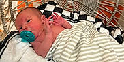 Chaseton joined the competition — help win amazing prizes! baby, black_and_white_blanket, blanket, child, comfort, cozy, cute, face, hand, indoors, infant, lying_down, newborn, orange_background, pacifier, person, resting, soft_texture, striped_blanket, woven_chair