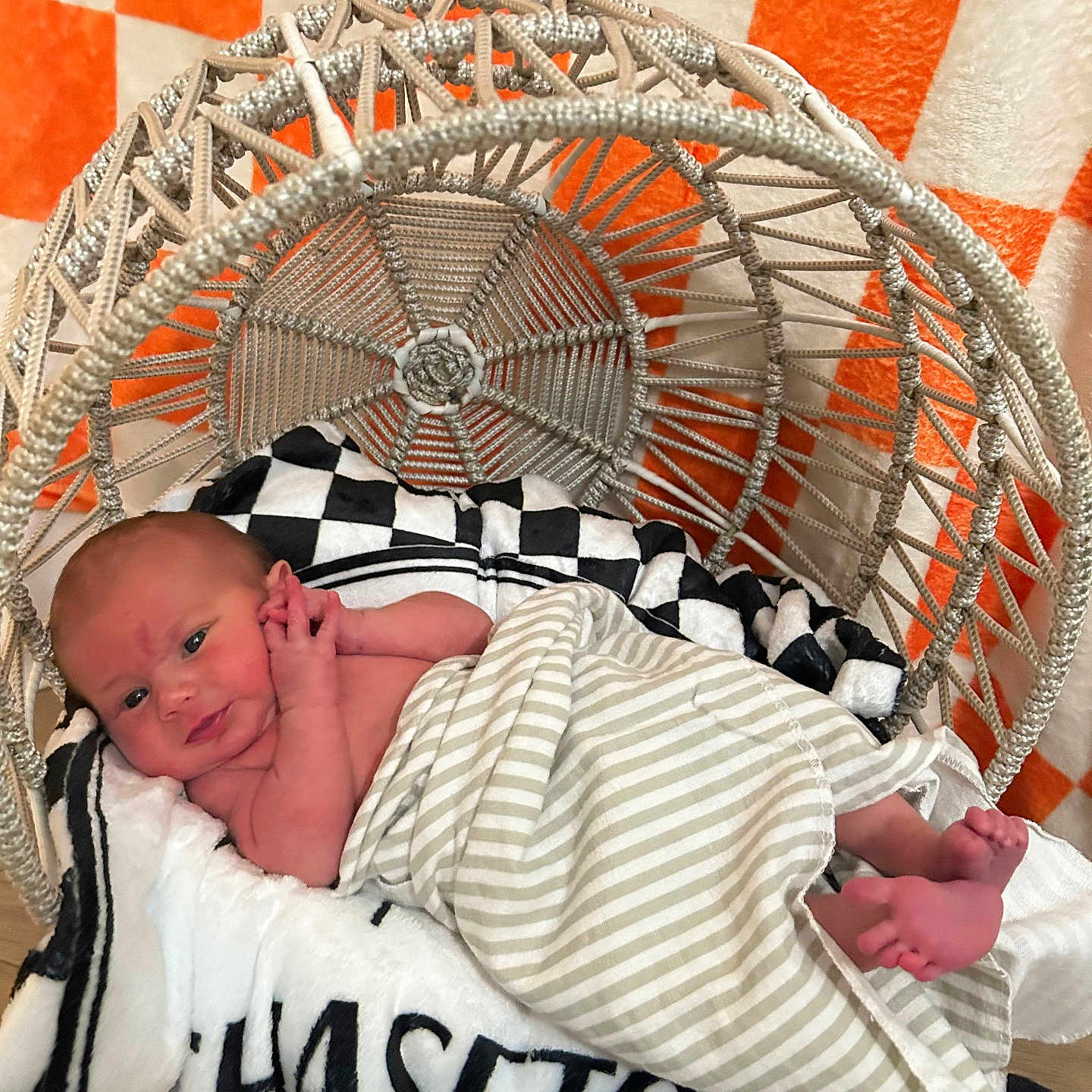 Chaseton is registered to the contest to win money with this photo: baby, basket, black, blanket, checkered_background, comfort, cozy, face, feet, hand, indoor, infant, lying_down, newborn, orange, soft_texture, striped_blanket, white, woven_chair, wrapped