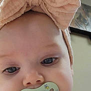 Tylie is registered to the contest to win money with this photo: baby, child, face, headband, bow, pacifier, indoor, clothing, white, gold, stars, cute, infant, portrait, closeup, expression, soft_light, skin, young, person