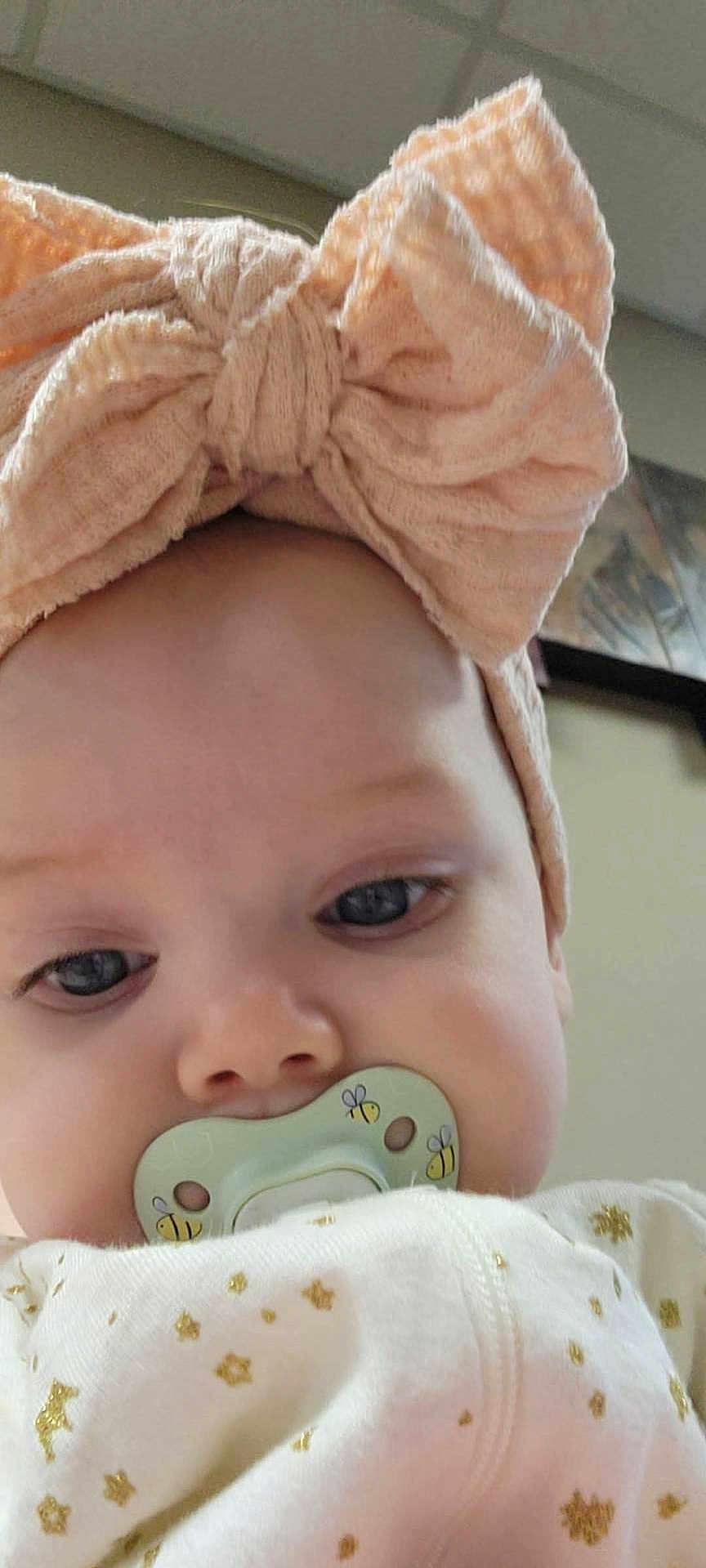 Tylie is registered to the contest to win money with this photo: baby, child, face, headband, bow, pacifier, indoor, clothing, white, gold, stars, cute, infant, portrait, closeup, expression, soft_light, skin, young, person