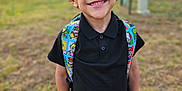 Milo joined the competition — help win amazing prizes! backpack, black_shirt, boy, cartoon_characters, casual_clothing, child, colorful, curly_hair, cute, daylight, field, grass, happy, jeans, nature, outdoor, portrait, smiling, standing, young