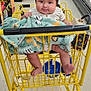 Darkiel joined the competition — help win amazing prizes! baby, shopping_cart, blanket, grocery_store, aisle, floor, baby_clothing, face, smiling, child, legs, hand, retail, products, shelf, supermarket, yellow_cart, indoor, person, cute