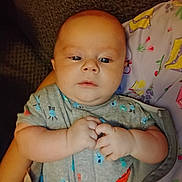 Remington is registered to the contest to win money with this photo: baby, infant, hands, onesie, clothing, face, person, cute, child, portrait, expression, indoor, skin, head, eyes, comfort, blanket, pattern, colorful, young