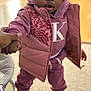Aunystee Star is registered to the contest to win money with this photo: toddler, child, hand_holding, pink_clothing, purple_hoodie, vest, boots, indoor, carpet, person, face, expression, winter_wear, playing, support, young_child, curious, standing, warm_clothing, home