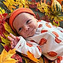 Easton joined the competition — help win amazing prizes! baby, infant, autumn, fall_leaves, pumpkin, orange_hat, pajamas, smile, hand_gesture, cute, seasonal, cozy, portrait, child, laying_down, indoors, colorful, decor, soft_texture, playful