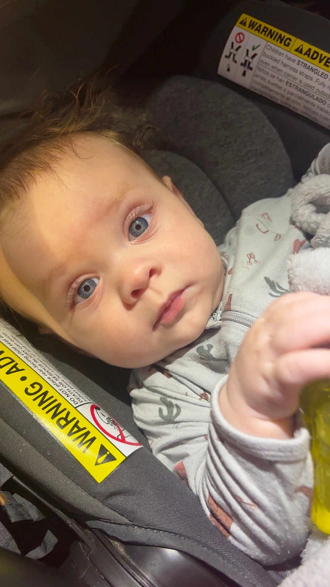 Waylon joined the competition — help win amazing prizes! baby, infant, blue_eyes, car_seat, onesie, child, hand, face, close_up, seat_belt_warning, soft_lighting, indoor, cute, young_child, expression, person, holding_object, hair, portrait, toddler