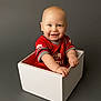 baby, child, infant, smiling, white_box, red_shirt, portrait, studio, sitting, hands, face, bald_head, cheeks, grey_background, one_person, cute, happy, blue_eyes, indoor, studio_lighting