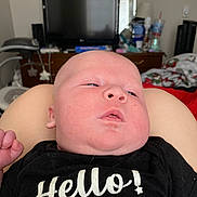Atlas joined the competition — help win amazing prizes! baby, infant, face, skin, clothing, black_shirt, text, hello, indoor, bedroom, television, furniture, person, newborn, resting, cute, child, head, expression, lying_down