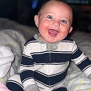 Tucker is registered to the contest to win money with this photo: baby, child, smiling, happy, onesie, striped_clothing, sitting, blanket, indoor, portrait, cute, infant, face, eyes, hand, cozy, soft, warm, baby_clothes, young_child