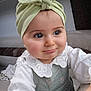 baby, child, headwrap, green, bow, white, collar, lace, dress, portrait, cute, smile, indoor, person, face, young_child, long_eyelashes, hand, seated, curious
