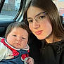 baby, child, woman, glasses, car_interior, denim, red_bow, casual_clothing, portrait, indoor, window, street_view, young_woman, face, person, smile, sitting, closeup, transportation, family