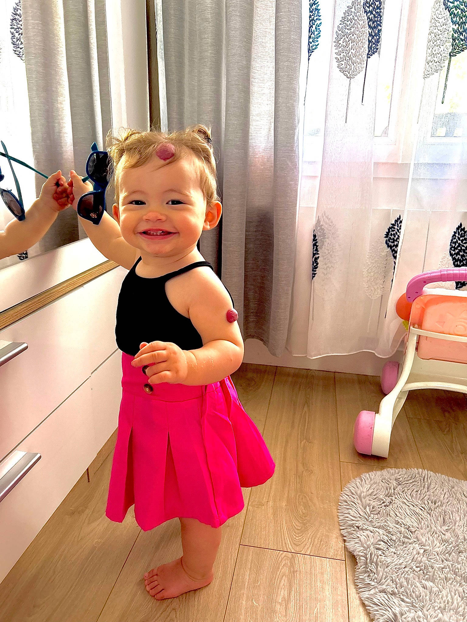 Maris Amalia a rejoint le concours — aidez-le/la à gagner de superbes lots ! arm, baby_toddler_clothing, curtain, finger, floor, flooring, gesture, happy, hardwood, joint, joy, person, pink, shoulder, skin, sleeve, smile, standing, thumb, toddler