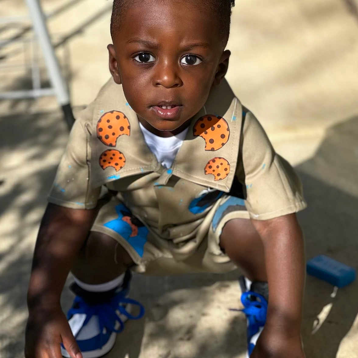 Akaiyo is registered to the contest to win money with this photo: blue_shoes, boy, casual, child, concrete, cookies_pattern, curious, expression, face, hair, hands, outdoor, playful, shadow, shirt, shorts, skin, sneakers, squatting, sunlight