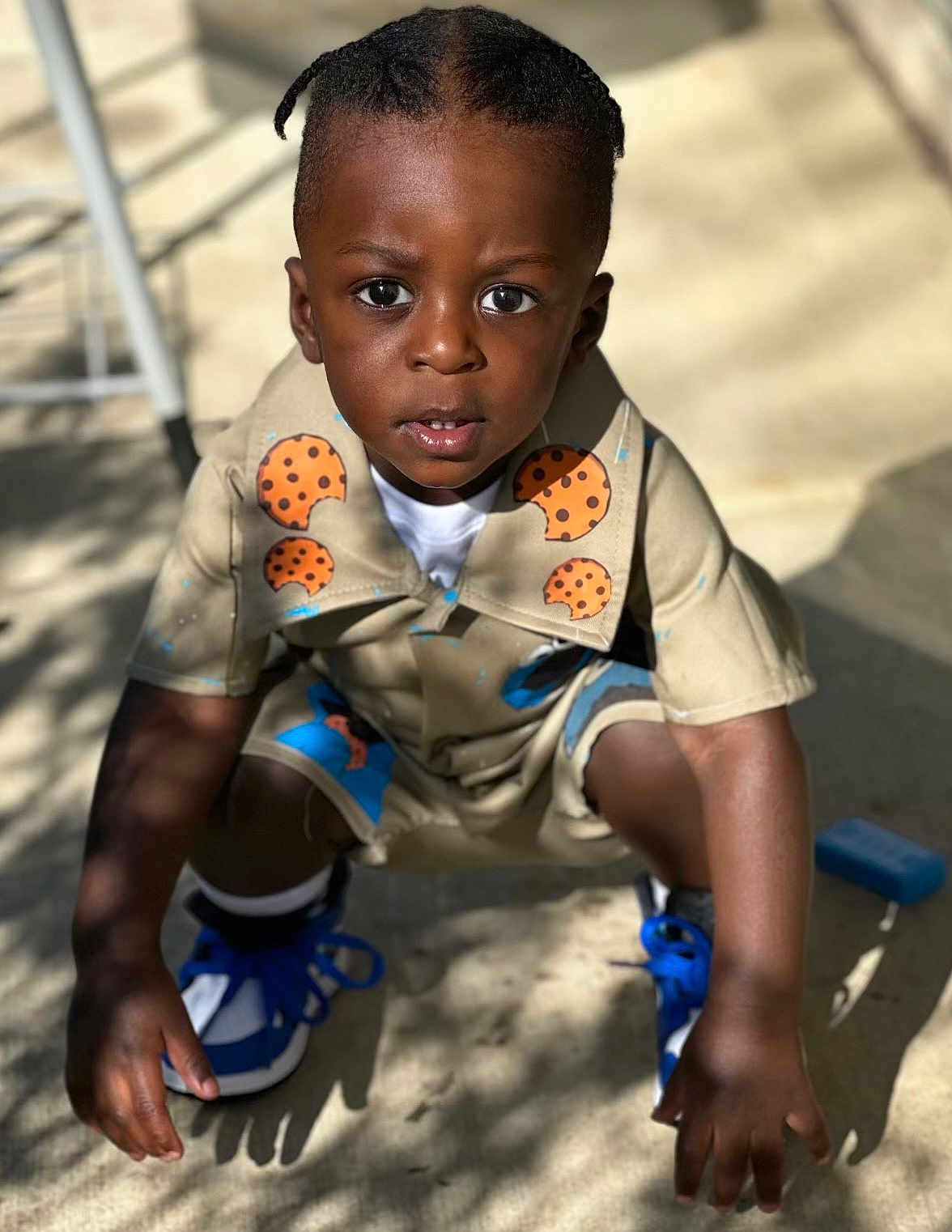 Akaiyo is registered to the contest to win money with this photo: child, boy, outdoor, squatting, curious, shorts, shirt, sneakers, blue_shoes, cookies_pattern, sunlight, shadow, expression, hair, face, skin, hands, concrete, playful, casual