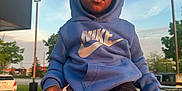 Akaiyo is registered to the contest to win money with this photo: toddler, child, hoodie, nike, jumpman, pants, hand, car, outdoor, parking_lot, sky, clouds, person, clothing, sunset_light, trees, vehicle, casual, holding_hand, urban