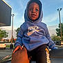 Akaiyo is registered to the contest to win money with this photo: toddler, child, hoodie, nike, jumpman, pants, hand, car, outdoor, parking_lot, sky, clouds, person, clothing, sunset_light, trees, vehicle, casual, holding_hand, urban