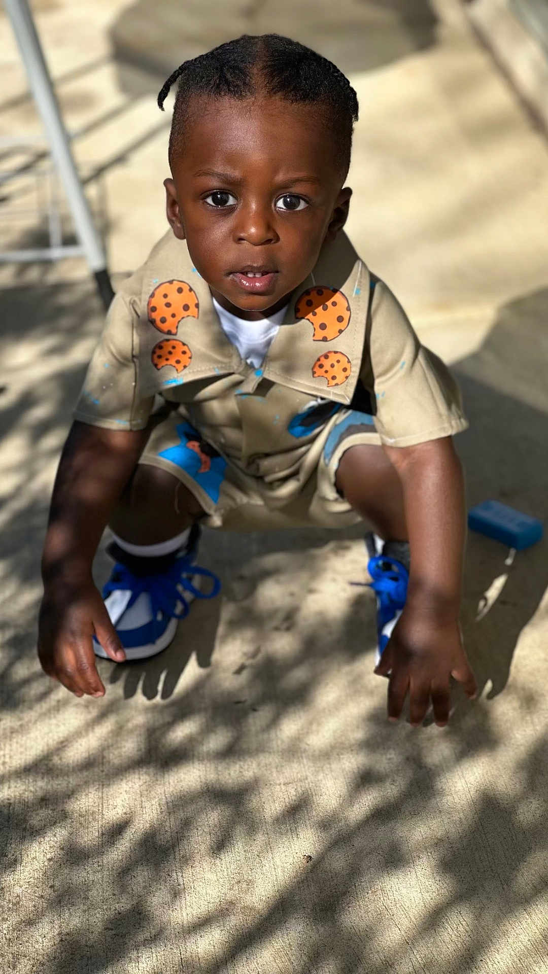 Akaiyo is registered to the contest to win money with this photo: child, toddler, squatting, outdoor, sunlight, shadow, concrete, shorts, shirt, blue_sneakers, curious, face, hair, playing, daylight, casual_clothing, young, person, expression, cookie_print