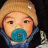 Damian is registered to the contest to win money with this photo: baby, child, pacifier, hat, knit_hat, denim_overalls, blanket, star_pattern, close_up, face, eyes, cute, infant, warm_clothing, baby_clothes, indoor, portrait, person, cozy, snuggled