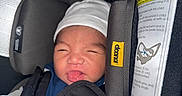 Damian joined the competition — help win amazing prizes! baby, black, blanket, blue, car_seat, child, clothing, cute, face, hat, indoors, infant, newborn, person, safety_label, seatbelt, smiling, soft_texture, tongue_out, white