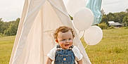 Walker joined the competition — help win amazing prizes! toddler, child, baby, overalls, denim, teepee, balloons, birthday, number_one, blanket, outdoor, grass, field, happy, smiling, curly_hair, sunlight, celebration, nature, portrait