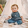 baby, child, denim_overalls, white_shirt, blanket, plaid, outdoor, grass, teepee, tent, curly_hair, blue_eyes, cute, sitting, portrait, infant, nature, daylight, smile, young