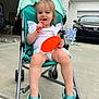 toddler, child, stroller, toy, orange_plate, orange_spoon, white_shirt, turquoise_shoes, concrete_driveway, car, garage, outdoor, smiling, happy, person, footwear, playing, daytime, house, casual