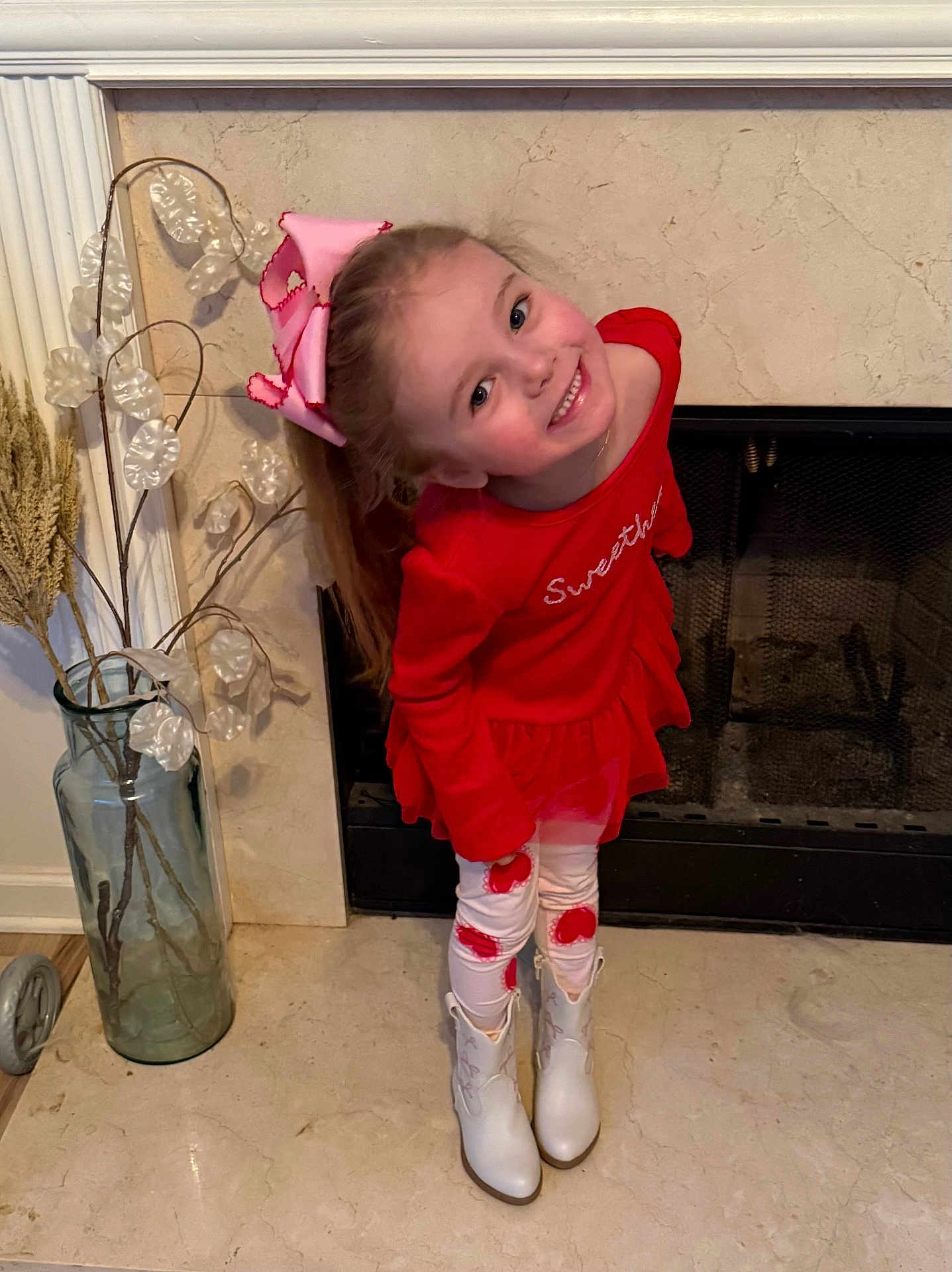 Sawyer Blake joined the competition — help win amazing prizes! bow, child, cute, decor, dried_plants, fashion, fireplace, floor, fun, girl, happy, home, indoor, playful, portrait, posing, red_dress, smiling, vase, white_boots