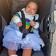 Keyvani joined the competition — help win amazing prizes! baby, booties, casual_wear, child, colorful_clothing, curly_hair, cute, fabric_texture, happy_expression, infant, outdoor, person, portrait, seat, seatbelt, sitting, soft_light, stroller, tutu, white_fabric