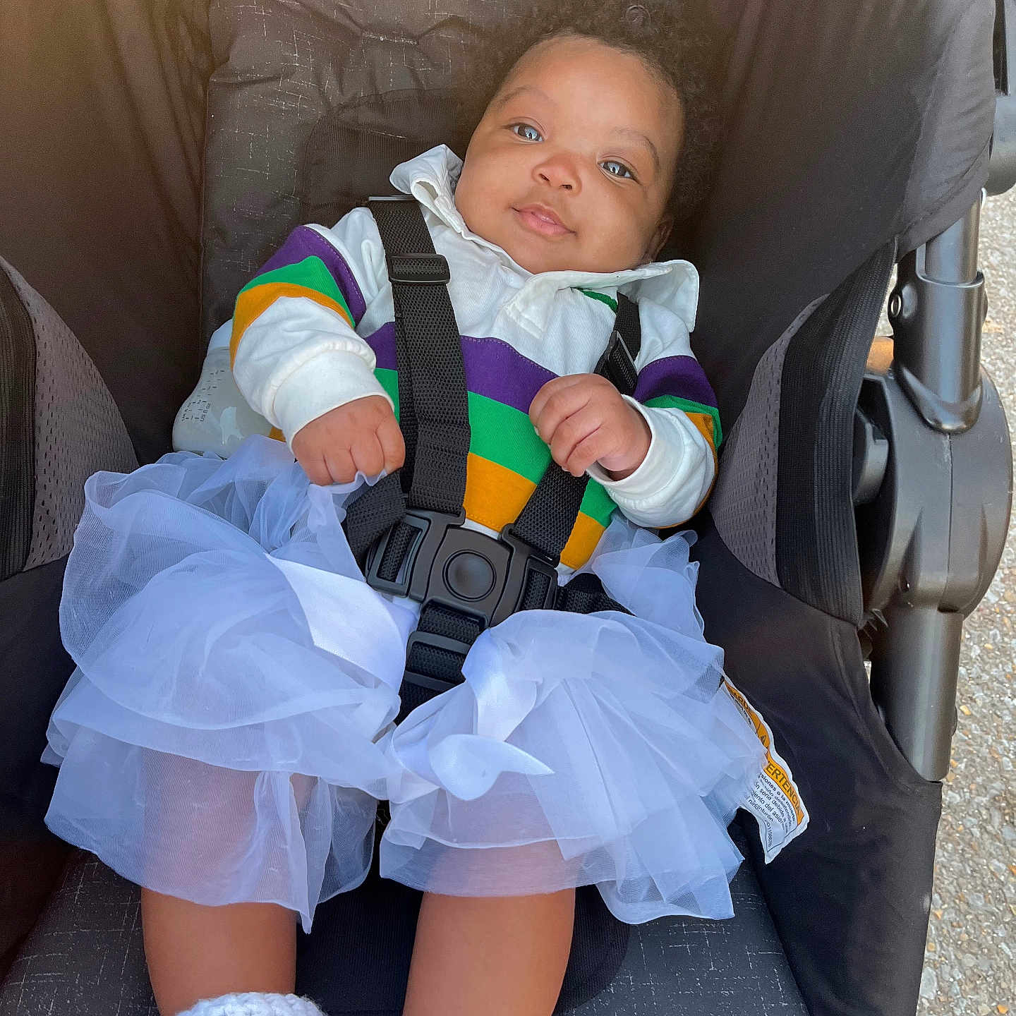 Keyvani joined the competition — help win amazing prizes! baby, booties, casual_wear, child, colorful_clothing, curly_hair, cute, fabric_texture, happy_expression, infant, outdoor, person, portrait, seat, seatbelt, sitting, soft_light, stroller, tutu, white_fabric