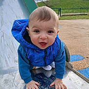 Zarek a rejoint le concours — aidez-le/la à gagner de superbes lots ! baby, blue_jacket, child, closeup, face, fence, grass, hands, happy, hood, jacket, metal, outdoors, play, playground, portrait, slide, smile, toddler, young